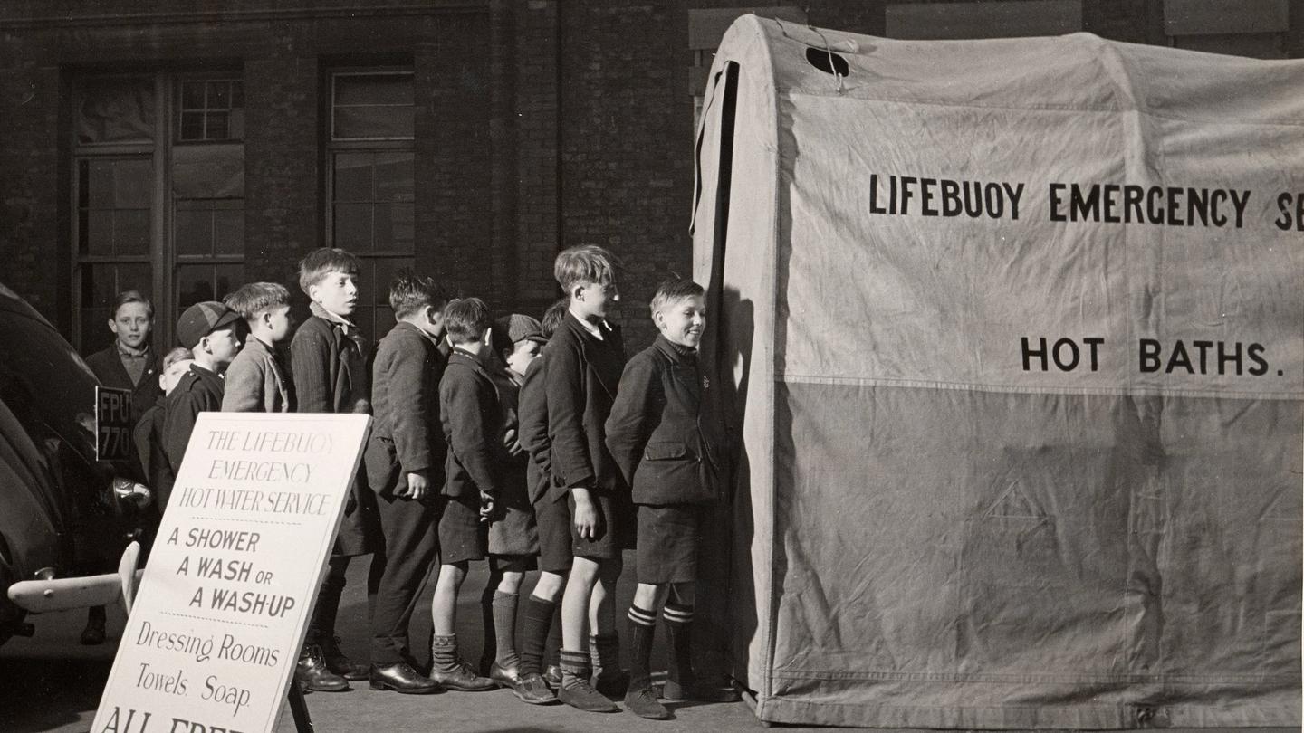 A photograph of young boys queuing for Lifebuoy's public aid emergency washing service during the Blitz in World War 2.