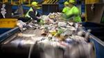 A group of people sorting through recycled material as it passes by on a conveyor belt