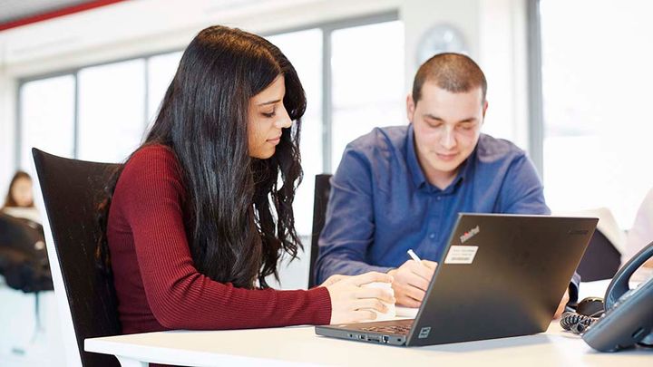 Graduates sitting at laptop