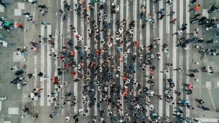 Aerial view photograph of a large number of people crossing a road. 