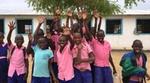 Smiling children in pink and blue shirts show their clean hands to the camera.