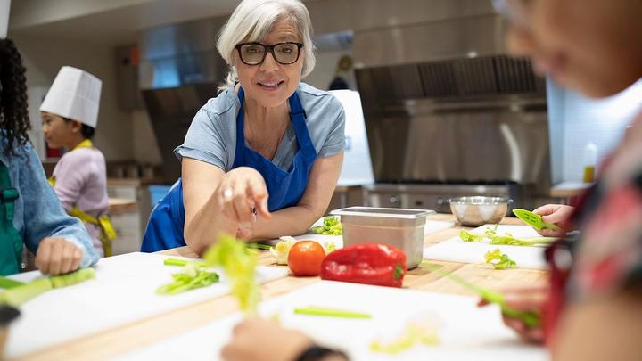 Woman in blue apron leaning over a kitchen counter