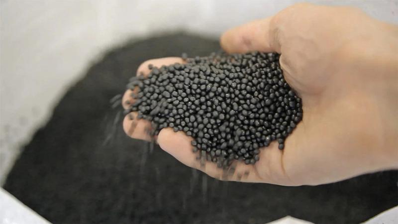 Hand holding black plastic pellets 