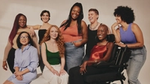 A photo from a Dove campaign featuring a group of eight diverse women, smiling at each other and at the camera.