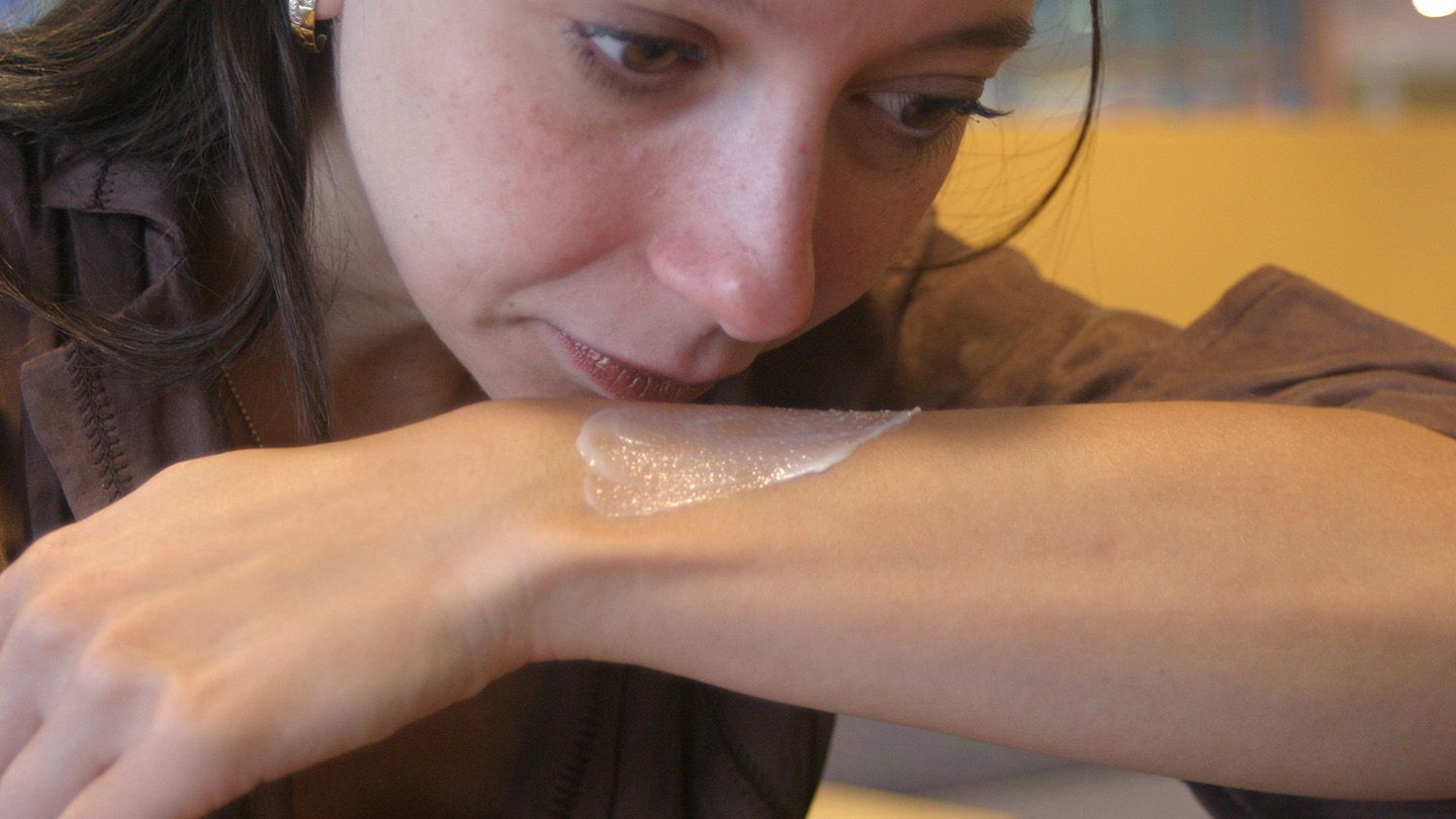 Woman smelling a product used on her arm