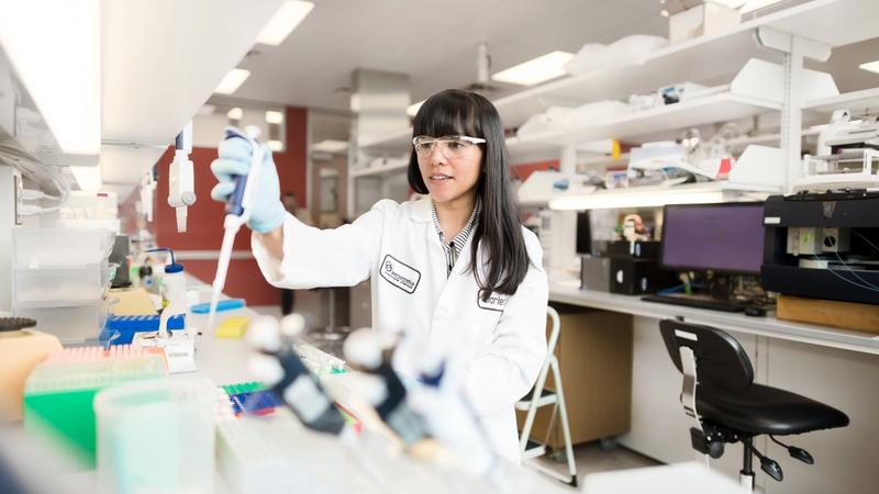 A woman in a white lab coat working at one of Geno’s biotech labs