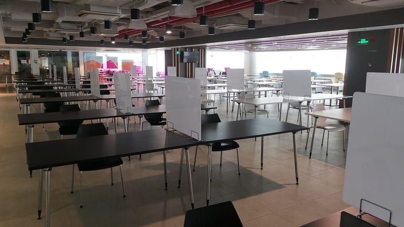The office canteen where tables and chair have been separated with dividers between them