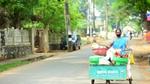 An image of a handcart with segregated dry waste. A lady wearing a blue sari is pushing the cart.