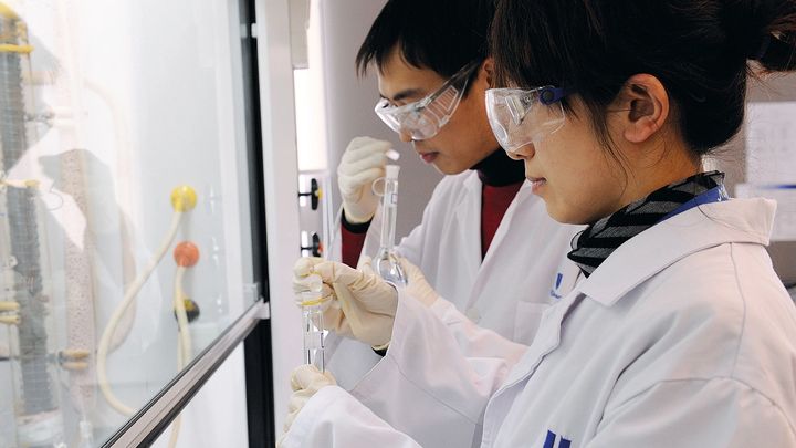 Two scientists in lab coats performing an experiment