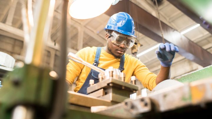A man in a factory with goggles and a hardhat