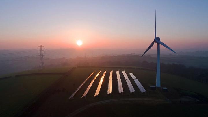 Aerial view of rural landscape showing wind turbine and solar panels in field.
