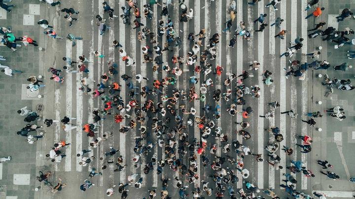 Aerial view photograph of a large number of people crossing a road.