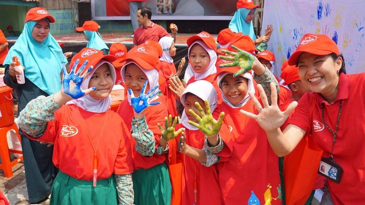 Schoolgirls wearing red Lifebuoy T shirts and caps make palm prints