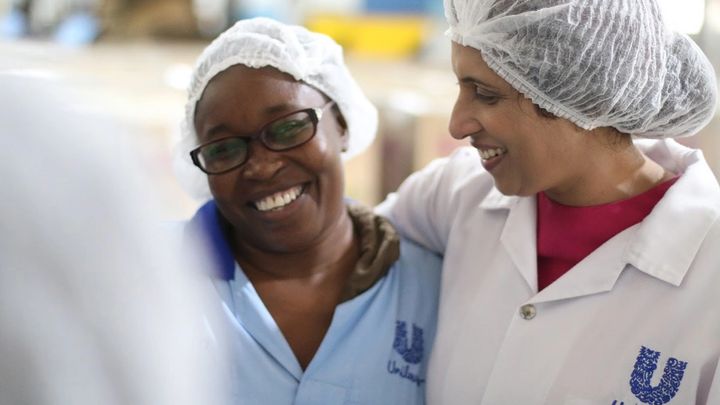 Two ladies in PPE and Unilever uniform with their arms around eachother smiling