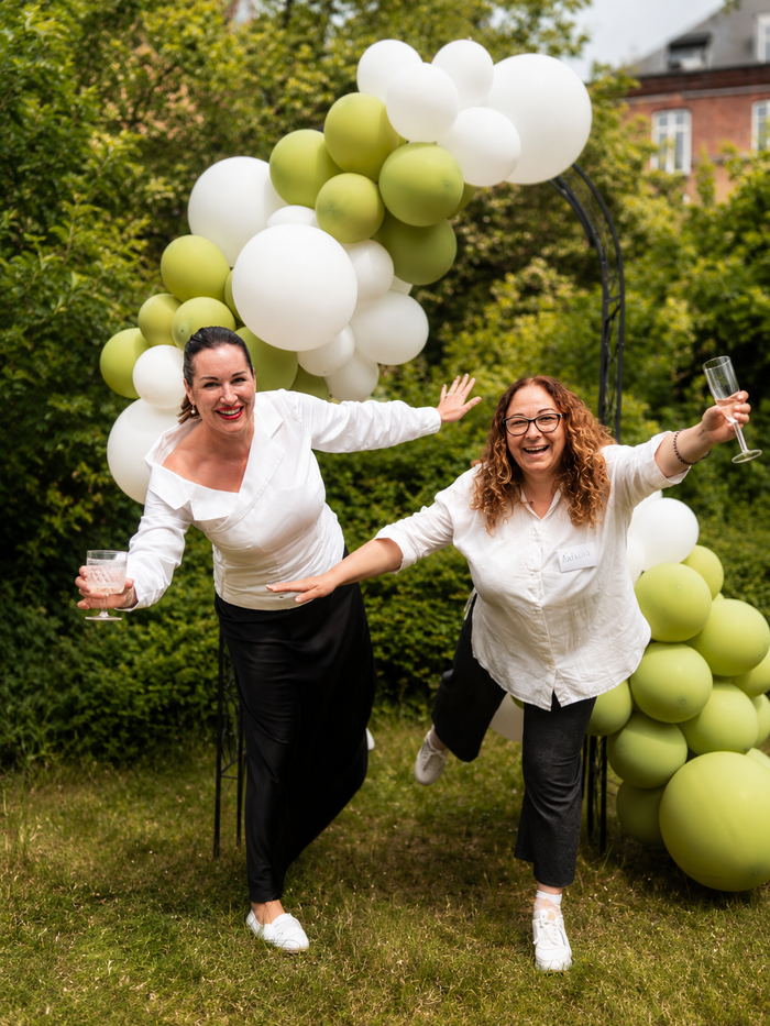 WECODA members celebrating in the garden by a green and white balloon arch