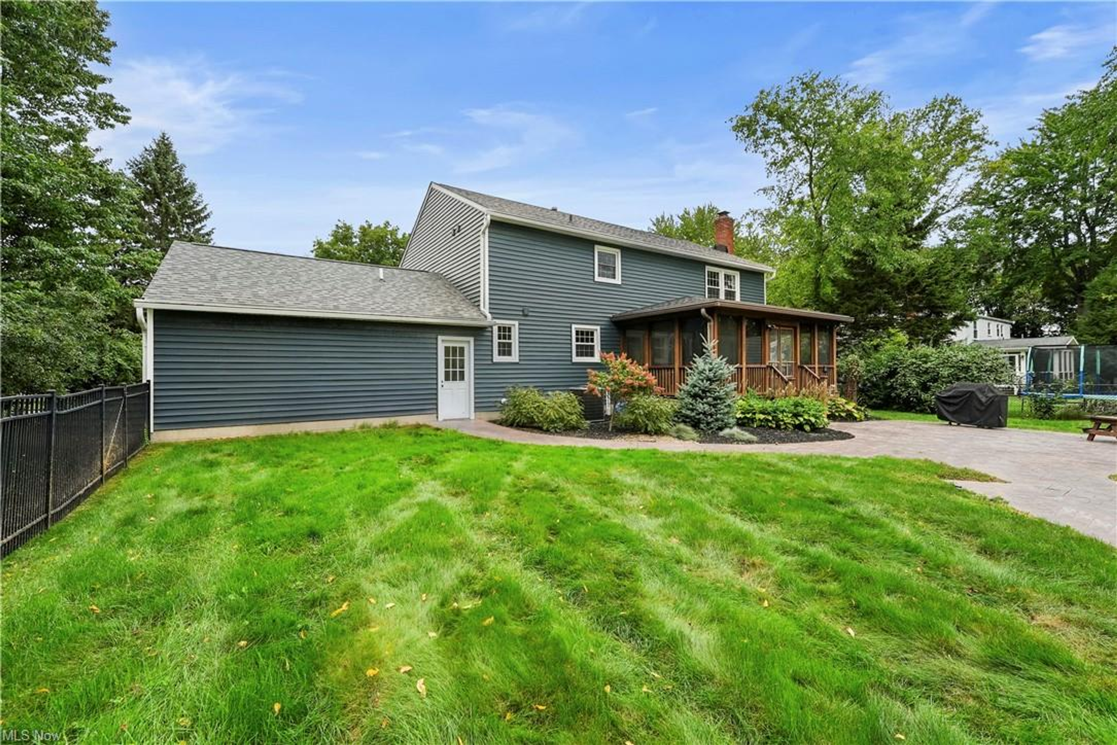 Rear exterior with screened porch, stamped-concrete patio, and fenced yard
