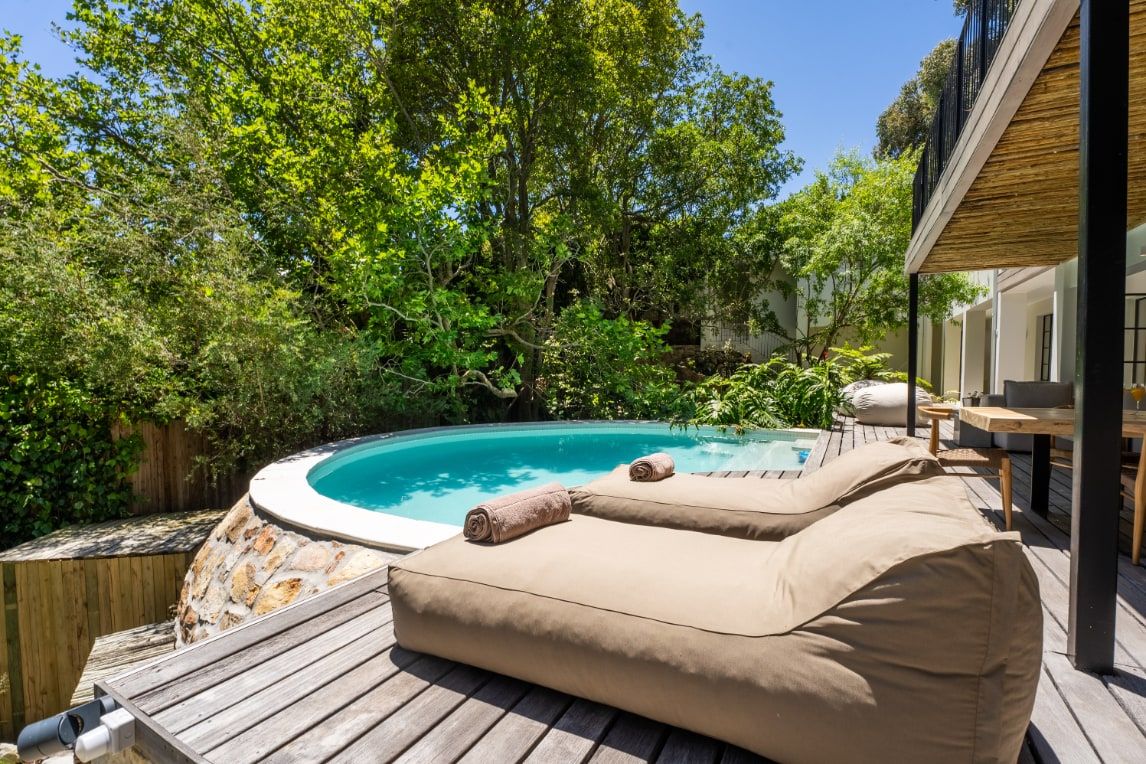 Private pool and timber sun deck surrounded by greenery