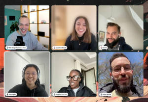 Full house video call with one member outside, the others laughing, sitting at their desks