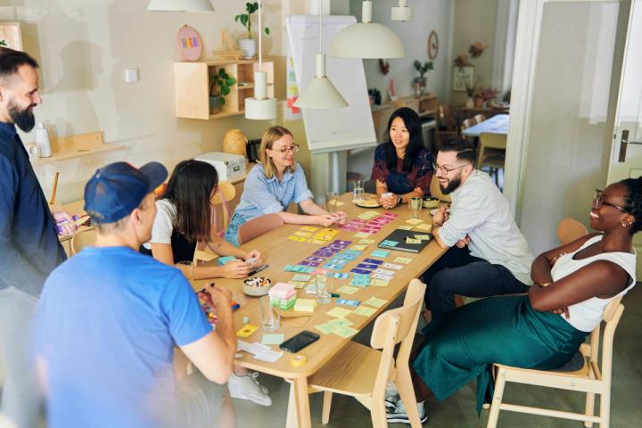 Team sitting around a large table that features a sorted expertise cards deck