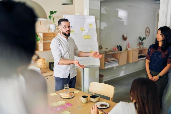 A team member standing in front of a flip chart elaborating on his sticky notes