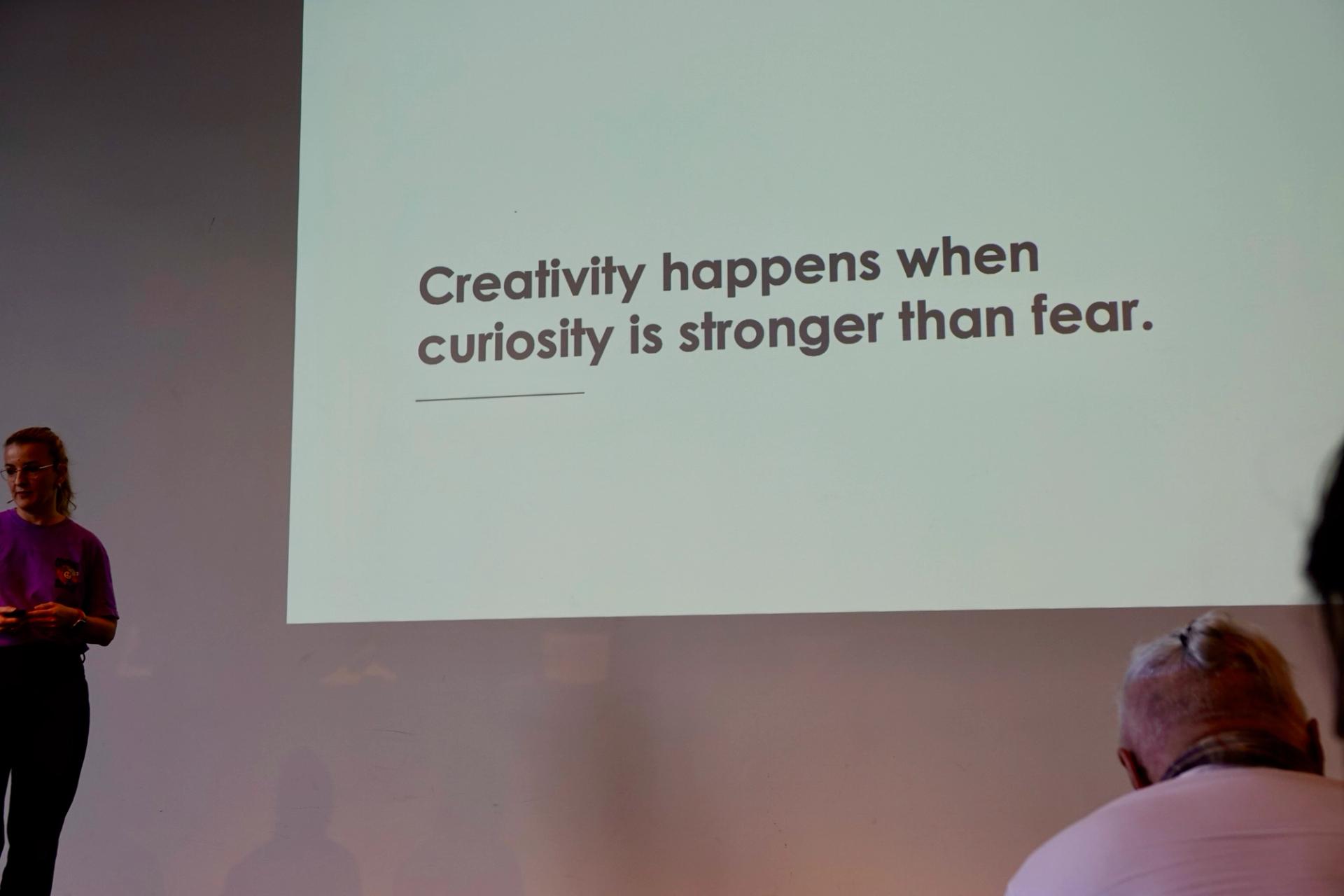 Stephanie Weber on stage showing my favorite quote: Creativity happens when curiosity is stronger than fear