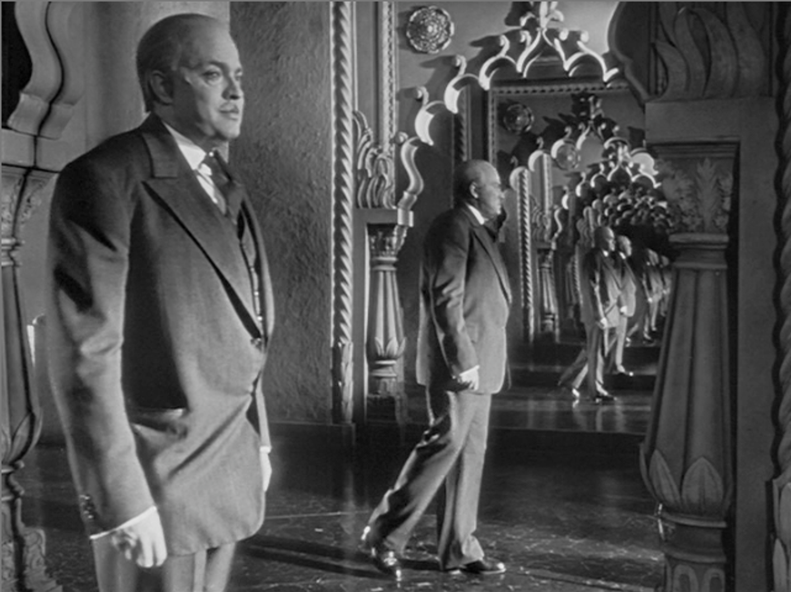 Charles Foster Kane as an older man is seen from a side angle, we can also see his reflection in the mirror. 