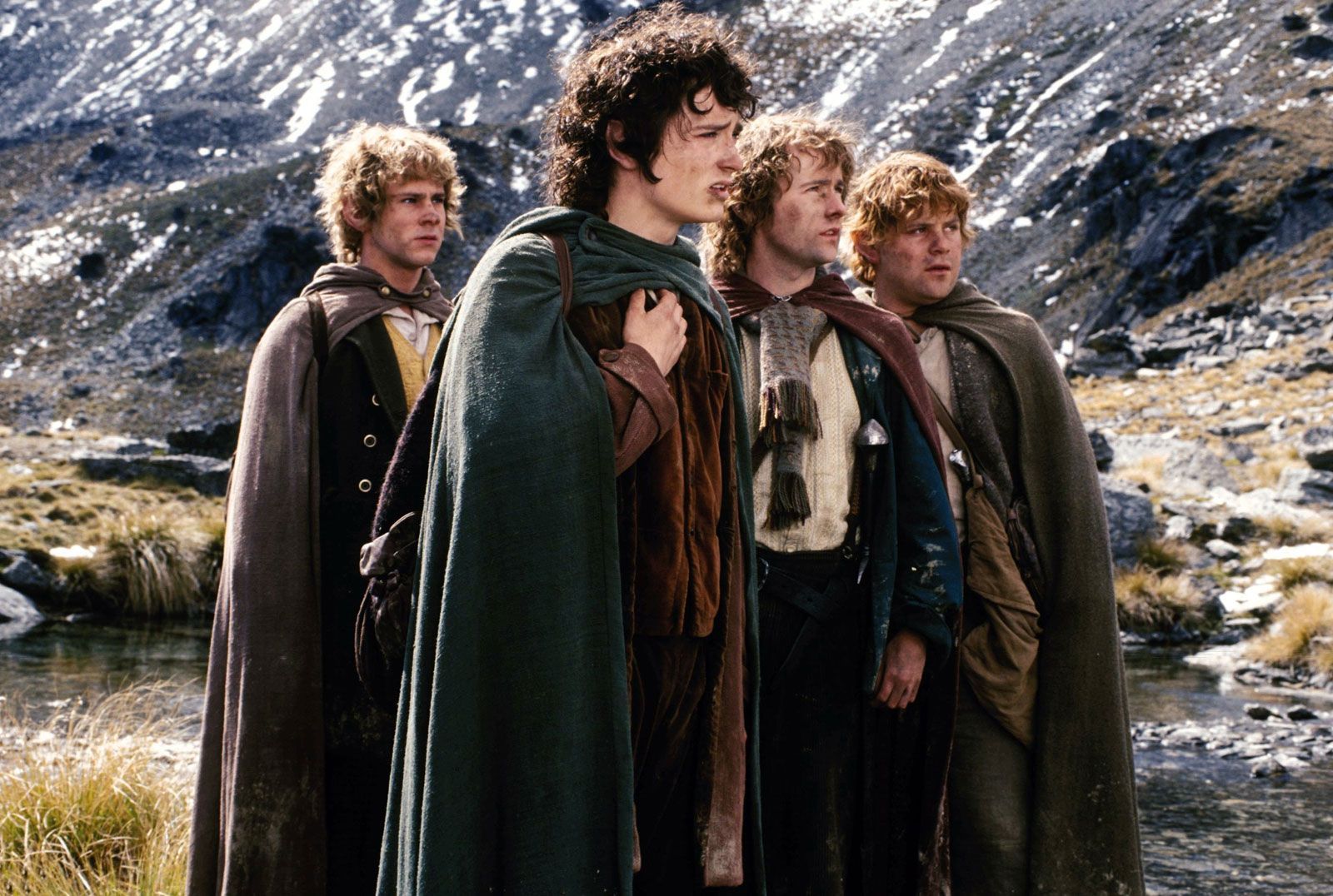 Frodo Baggins, the main protagonist in Fellowship of the ring surrounded by Sam and the others in the mountains.