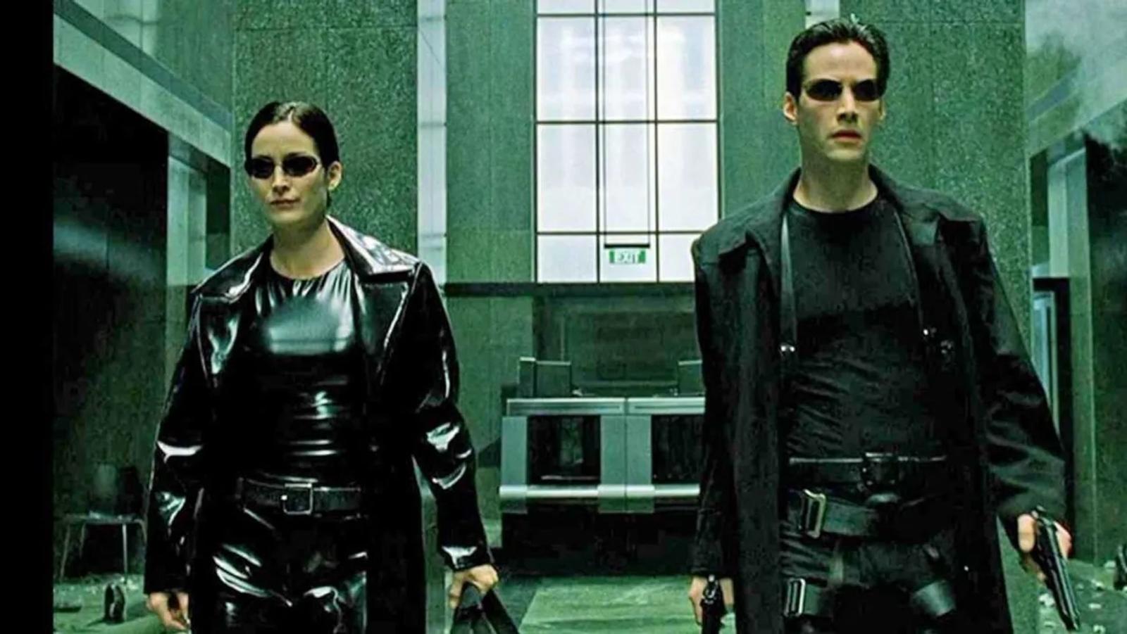 Neo and Trinity from The Matrix walking down a hallway holding weapons.