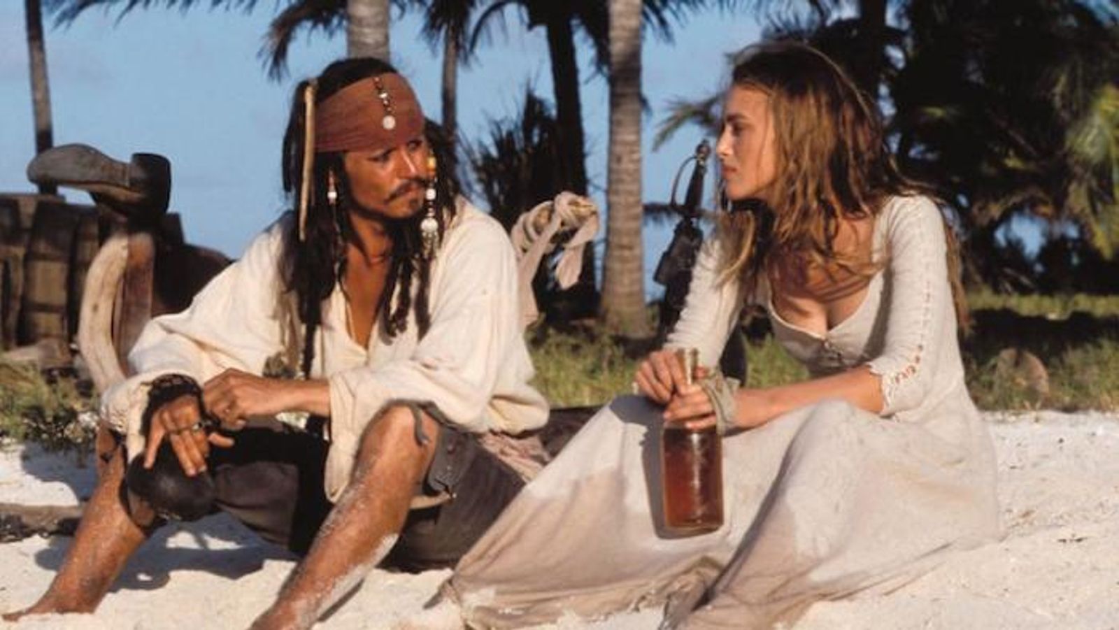 Johnny Depp as Jack Sparrow and Keira Knightley as Elizabeth Swann in Pirates of the Caribbean: The Curse of the Black Pearl. They are sitting on a  Caribbean beach discussing life. 