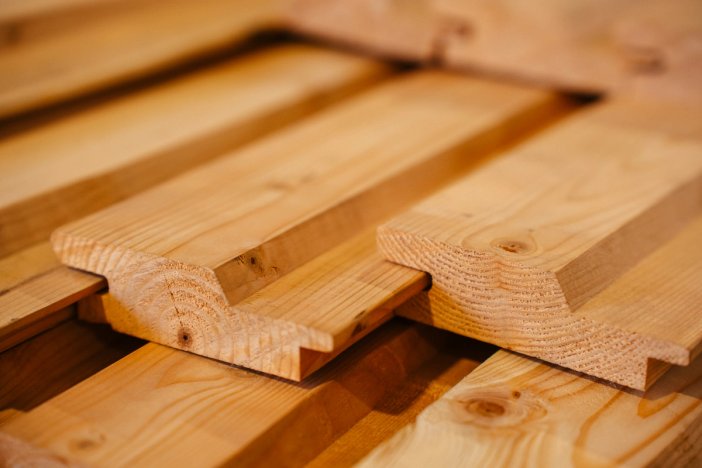 Stack of light-colored wood planks with interlocking profiles.