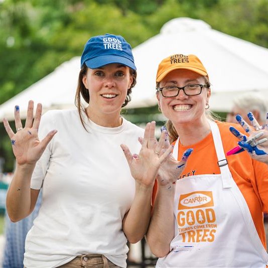 two women are standing next to each other with their hands painted blue .