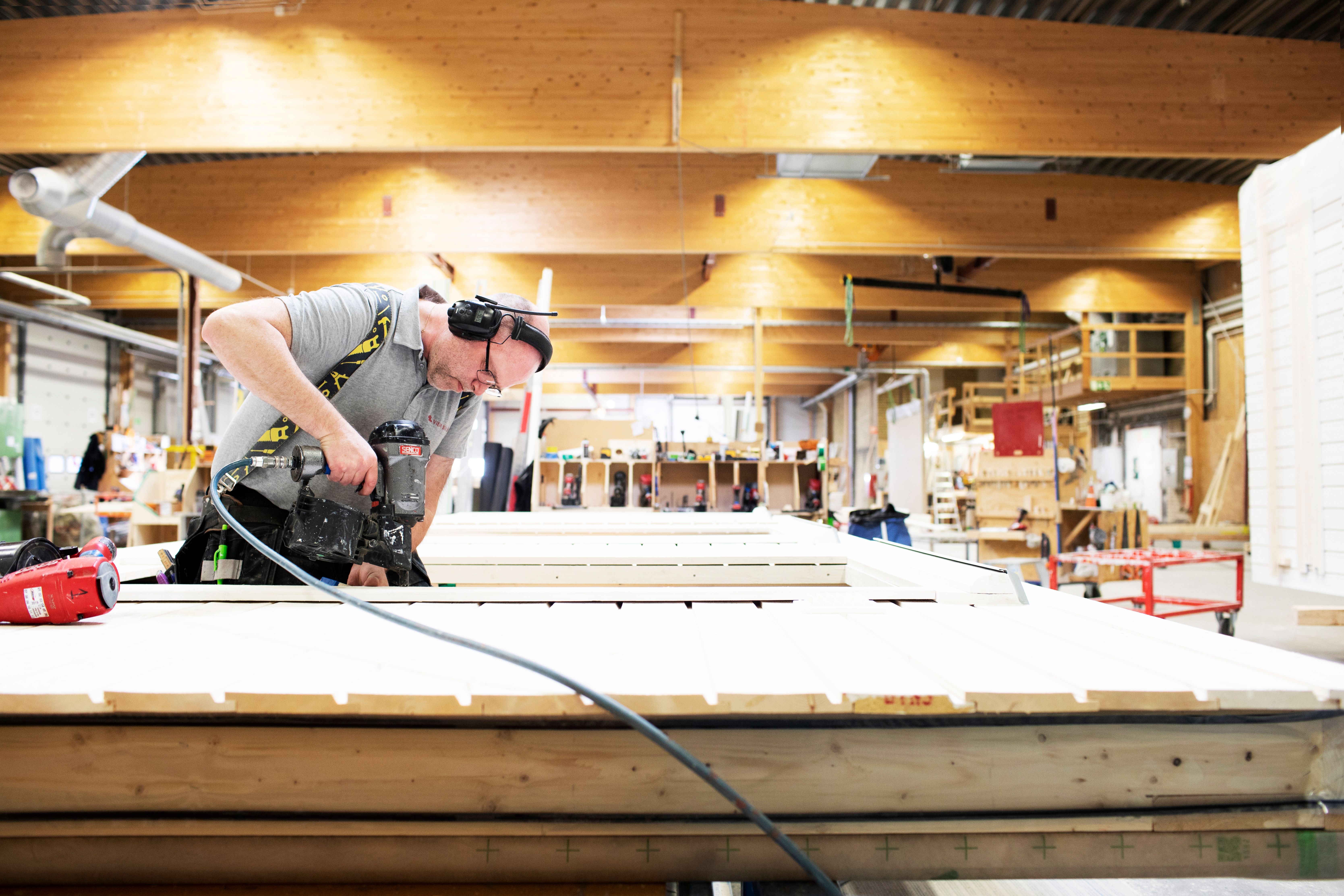 a man is cutting a piece of wood with a circular saw in a factory .
