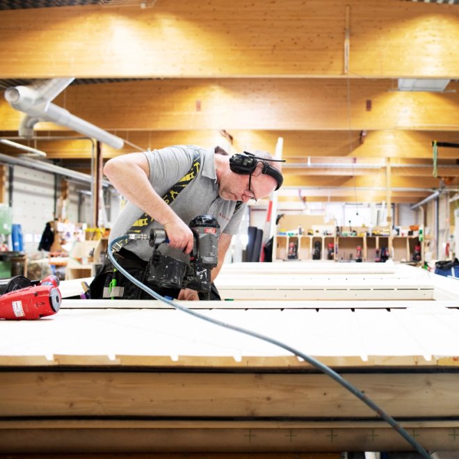a man is cutting a piece of wood with a circular saw in a factory .