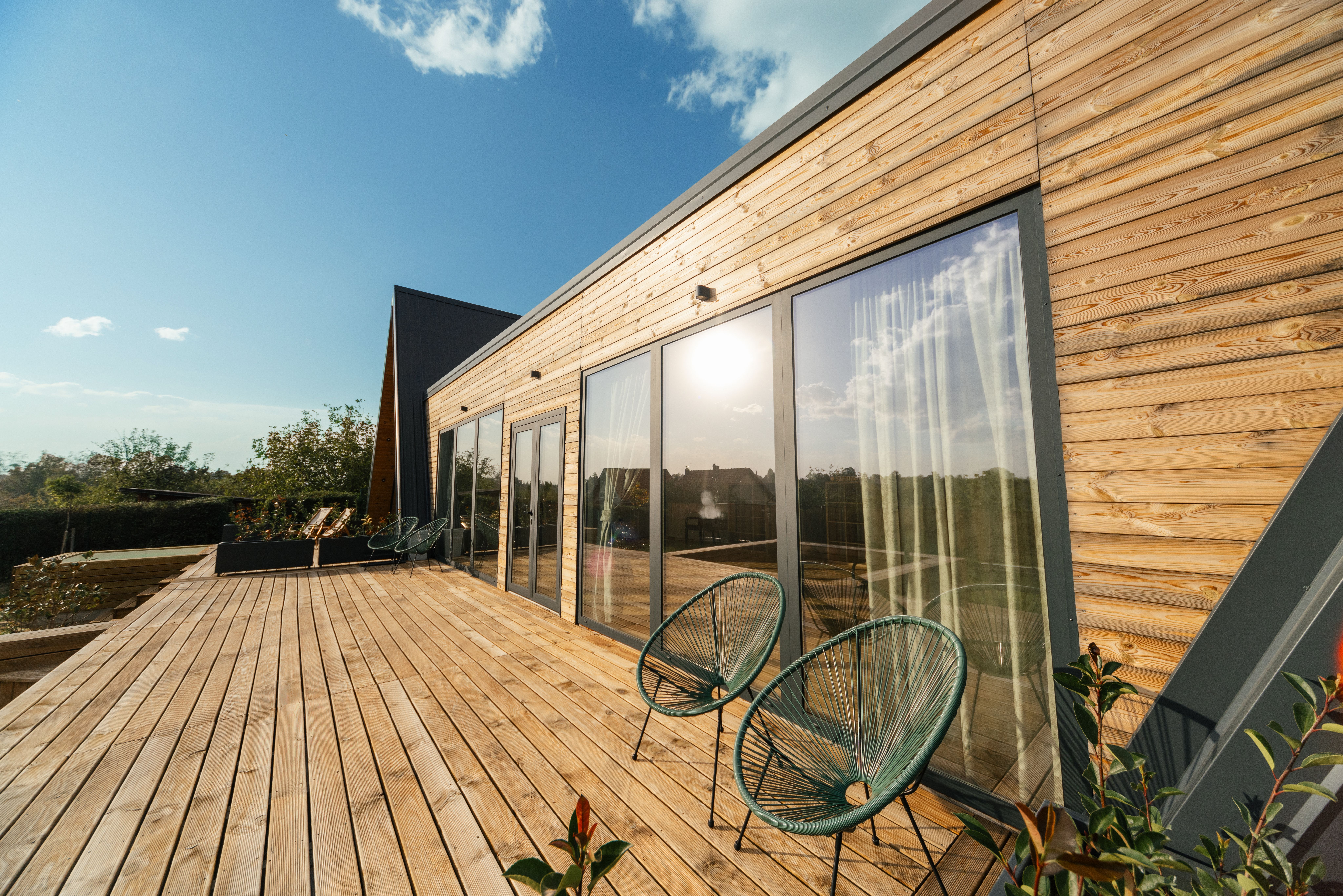 a wooden deck with chairs and a table in front of a house .