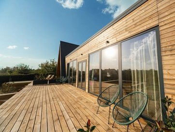 a wooden deck with chairs and a table in front of a house .