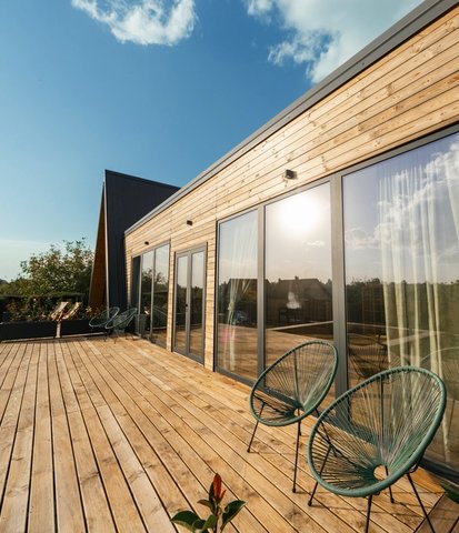 a wooden deck with chairs and a table in front of a house .