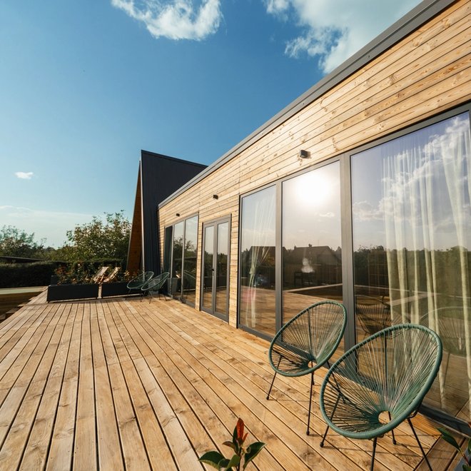 a wooden deck with chairs and a table in front of a house .