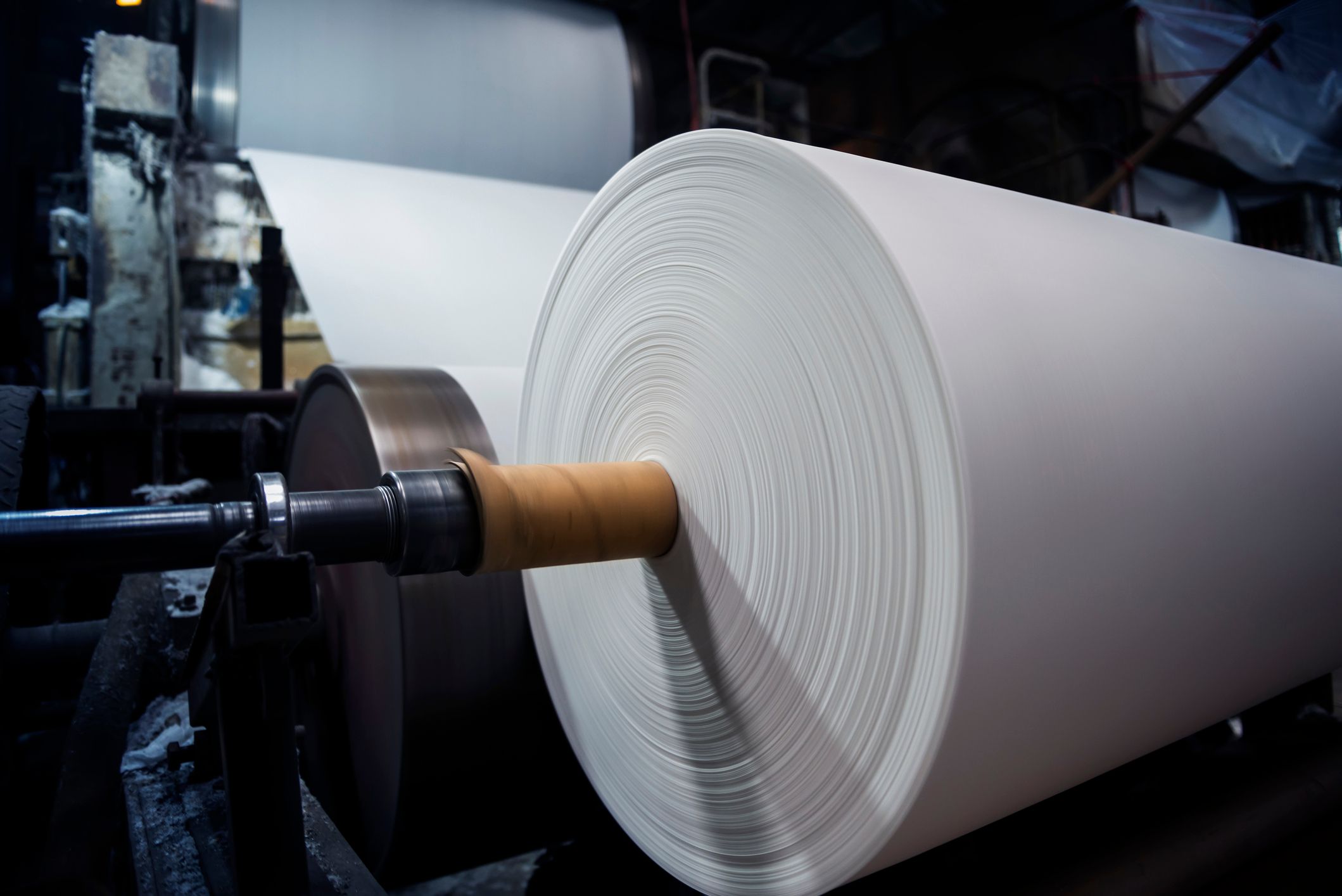 a large roll of paper is being rolled on a machine in a factory .