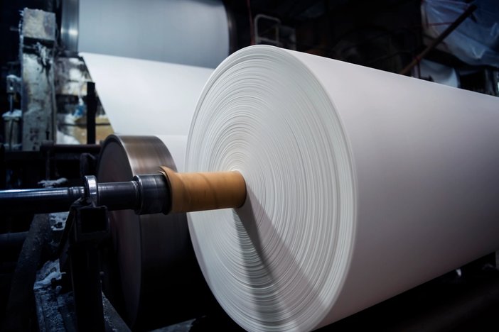 a large roll of paper is being rolled on a machine in a factory .