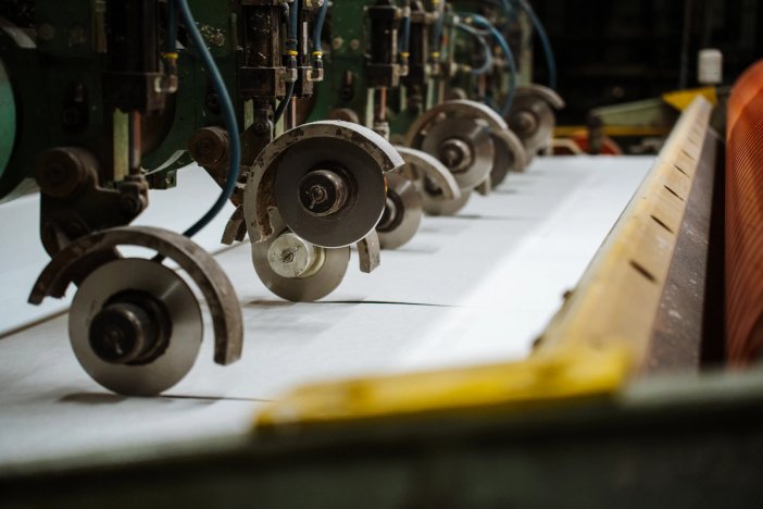 a machine is cutting pulp sheets on a conveyor belt in a factory .