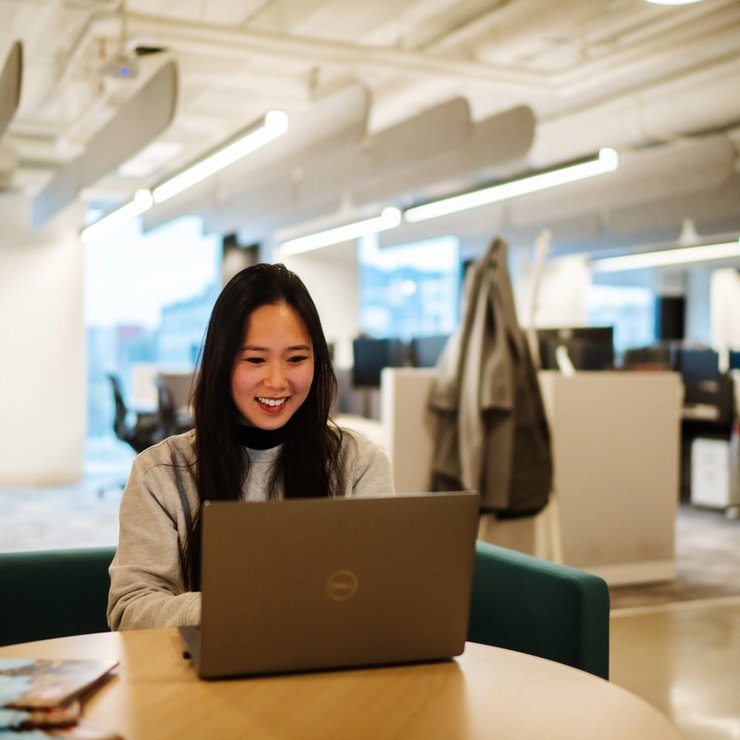 a woman is sitting at a table using a laptop computer .