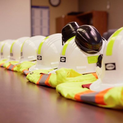 a row of hard hats and safety vests are lined up on a table .