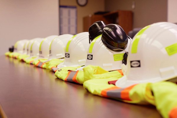 a row of hard hats and safety vests are lined up on a table .