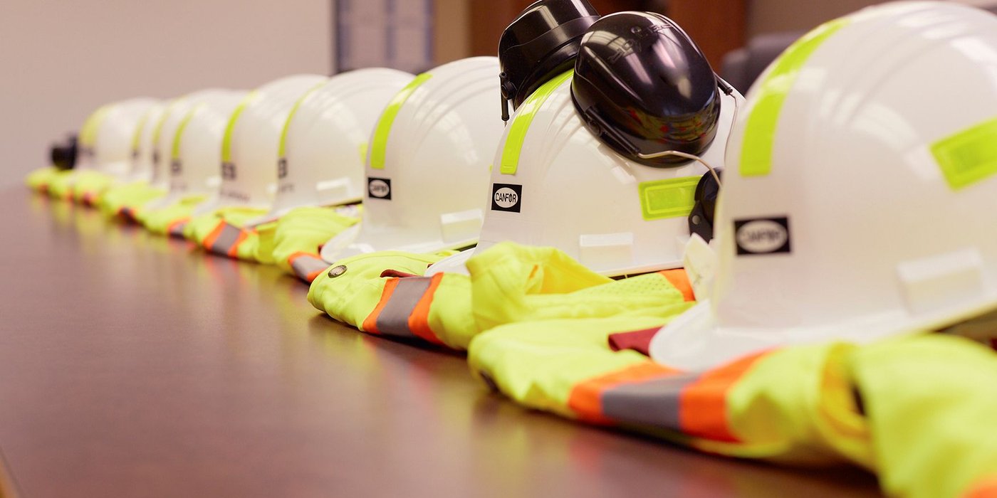 a row of hard hats and safety vests are lined up on a table .