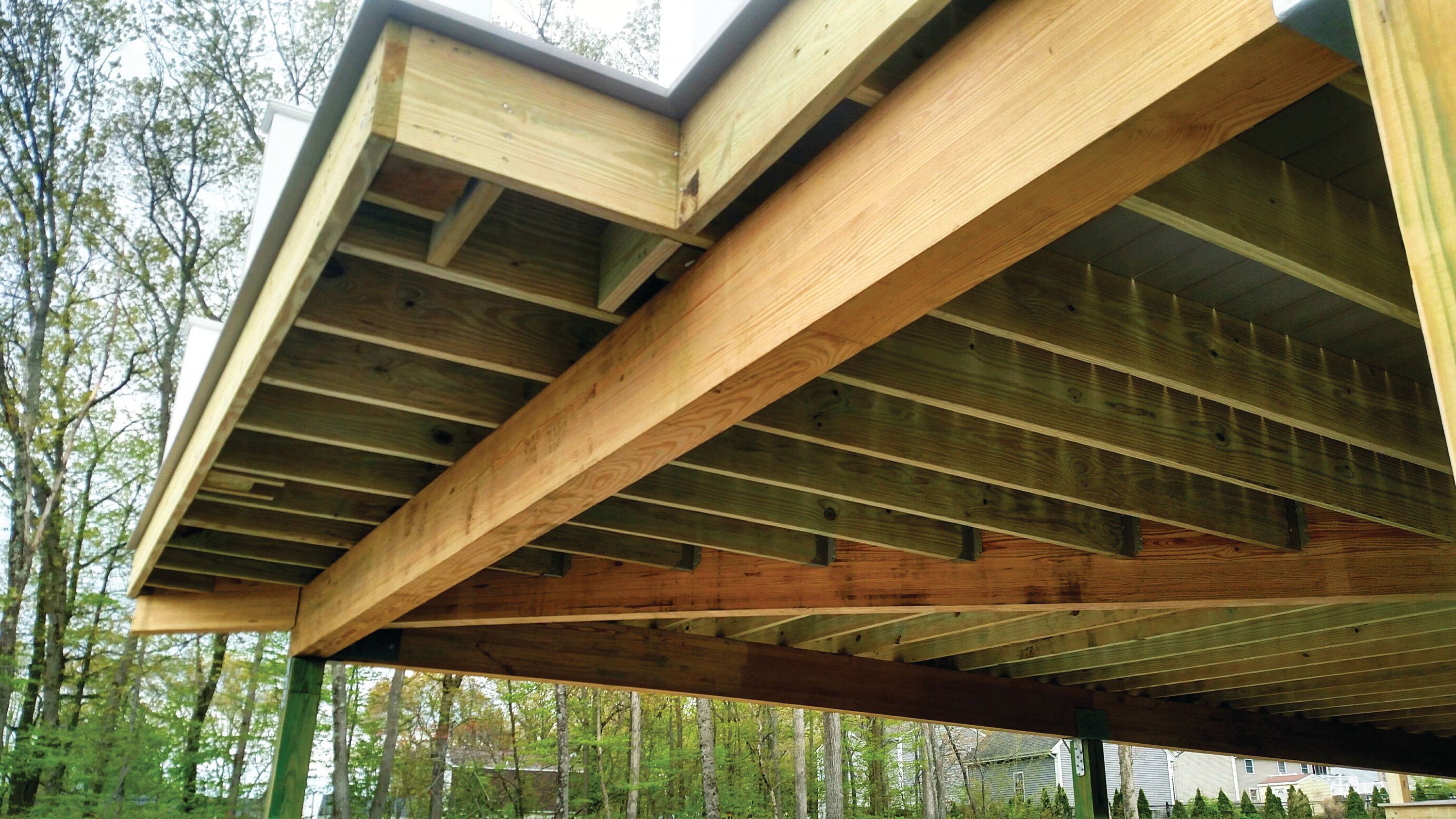 the ceiling of a wooden deck is being built .