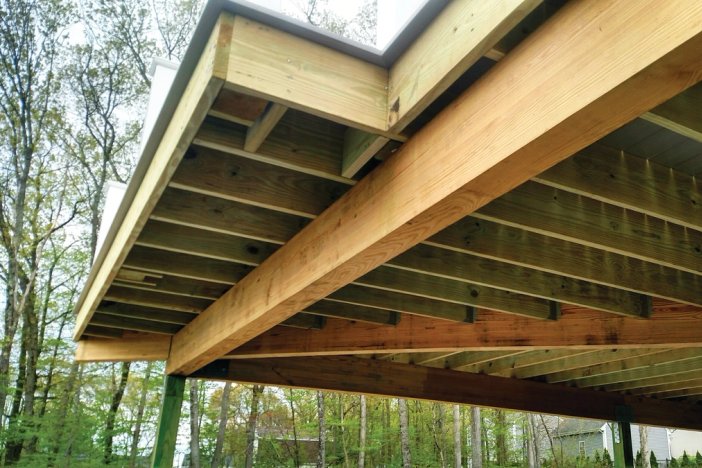 the ceiling of a wooden deck is being built .