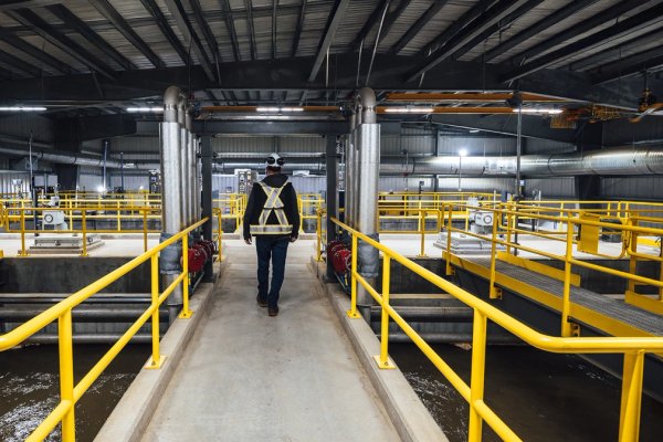a man is walking on a walkway at Canfor's Prince George Water Treatment facility.