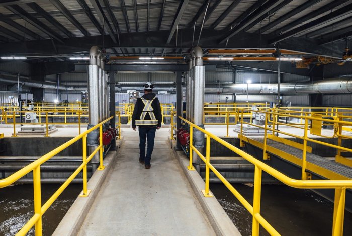 a man is walking on a walkway at Canfor's Prince George Water Treatment facility.