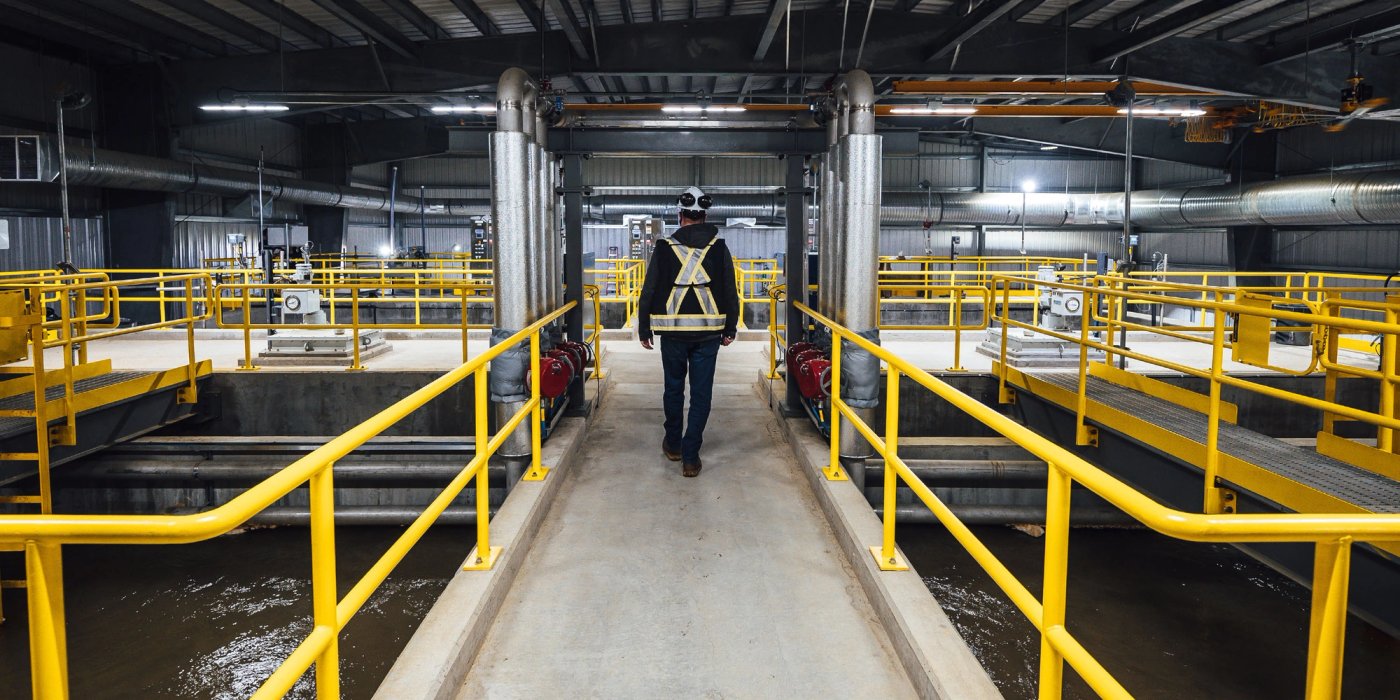 a man is walking on a walkway at Canfor's Prince George Water Treatment facility.