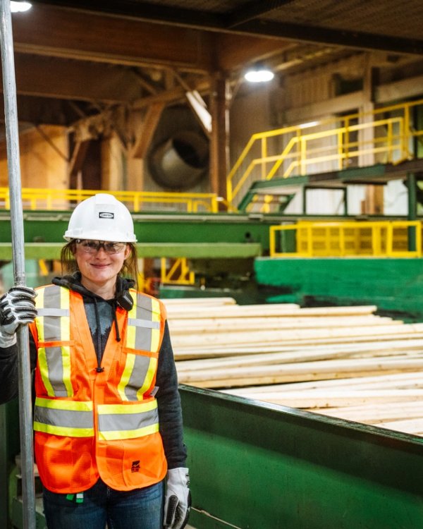 a woman is standing in a factory holding a pole .